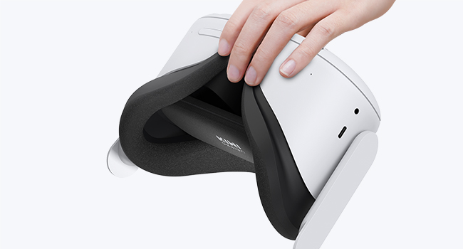 A virtual reality headset with a black controller being inserted into the top of the device.